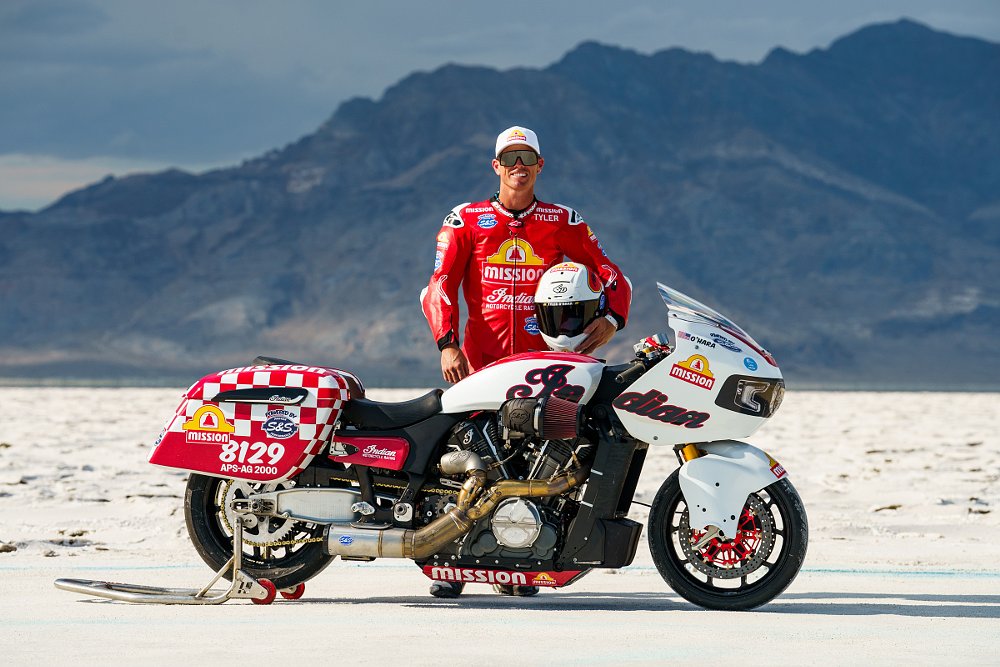 Tyler O'Hara posing with his Challenger race bike on the Salt Flats, mountains in the background