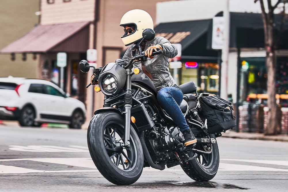A female rider navigates a city street aboard the 2026 Honda Rebel 300 E-Clutch.